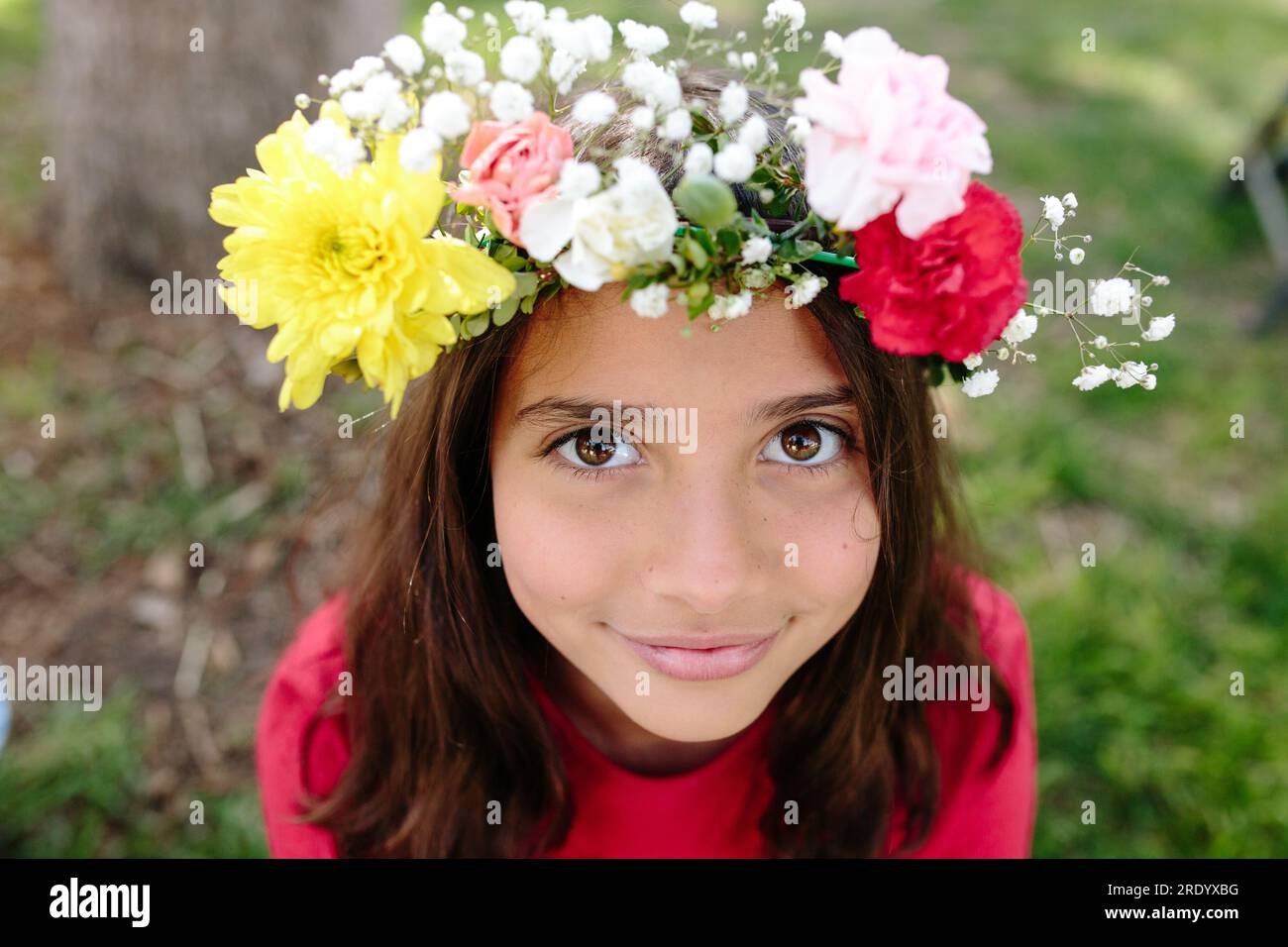 Tween ragazza con corona di fiori dal vivo guarda in alto la telecamera Foto Stock