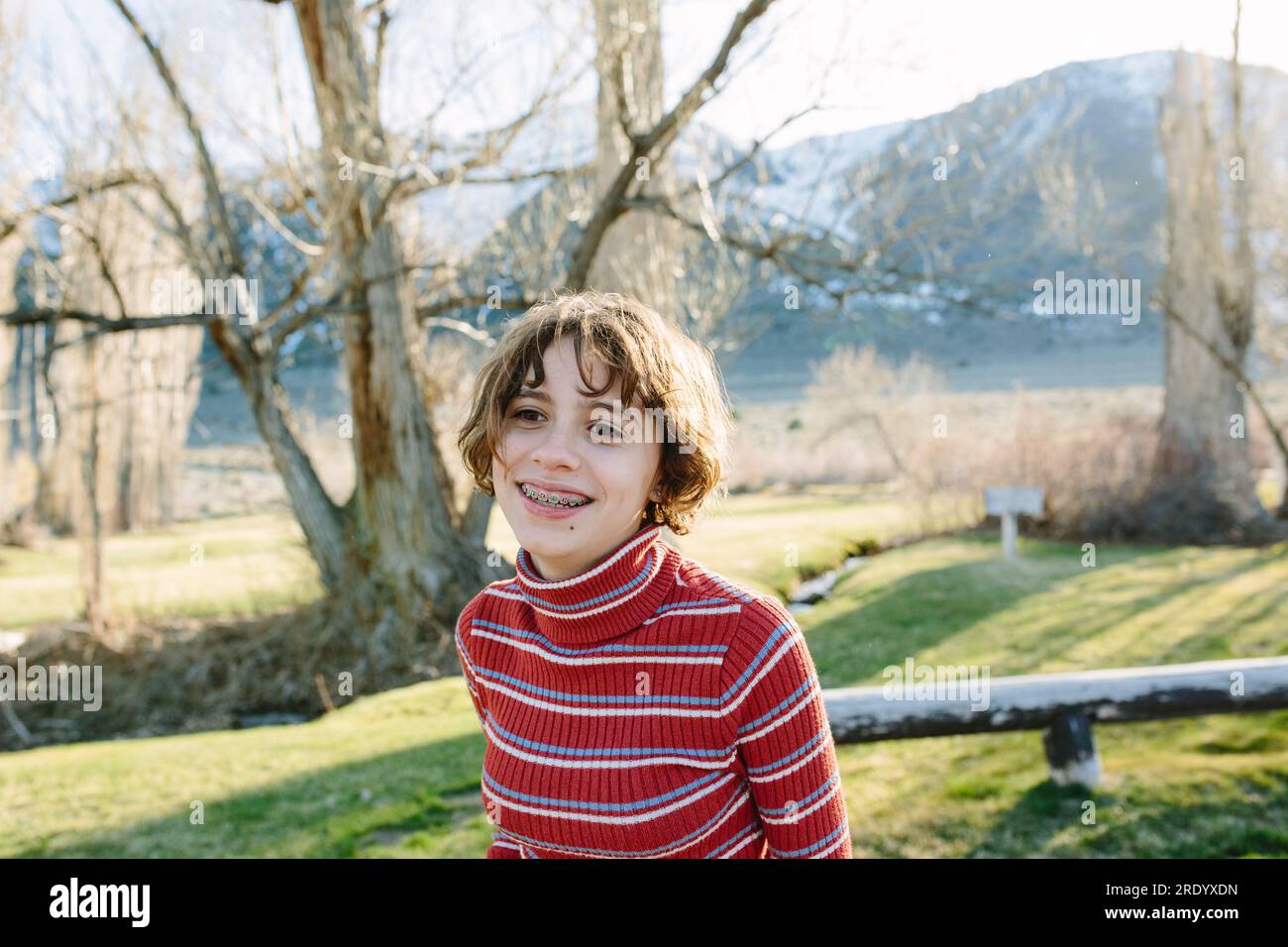 Ragazza adolescente con bretelle e capelli corti sorride mentre si trova in un parco Foto Stock Ragazza adolescente con bretelle e capelli corti sorride mentre si trova in un parco Foto Stock