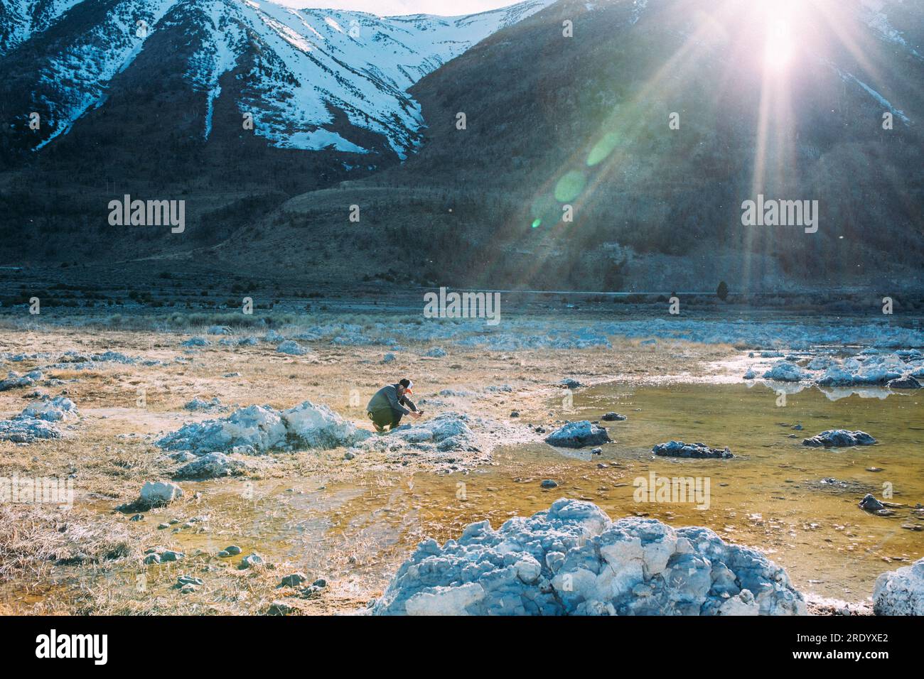 Foto del sole di un uomo in lontananza che scatta una foto con il suo telefono Foto Stock