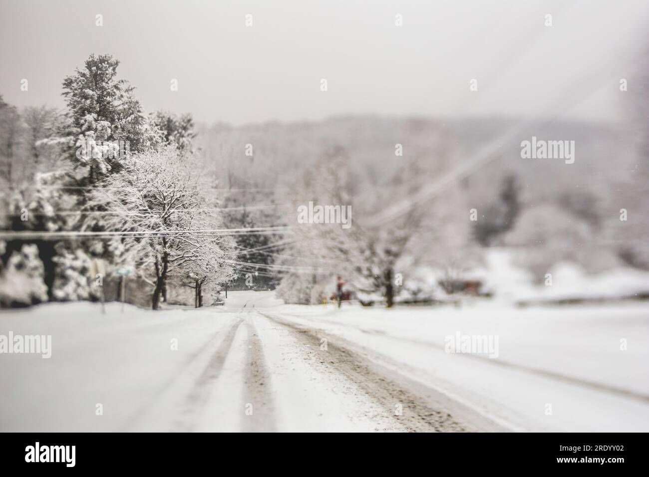 Strada residenziale ricoperta di neve nel New England rurale durante l'inverno Foto Stock
