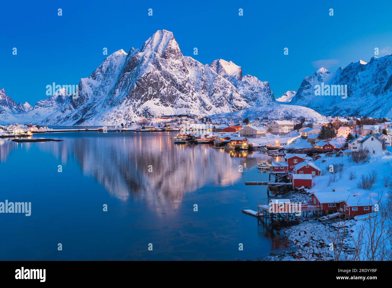 Il picco Olstind si specchia nel mare ghiacciato al crepuscolo, Reine, Norvegia Foto Stock