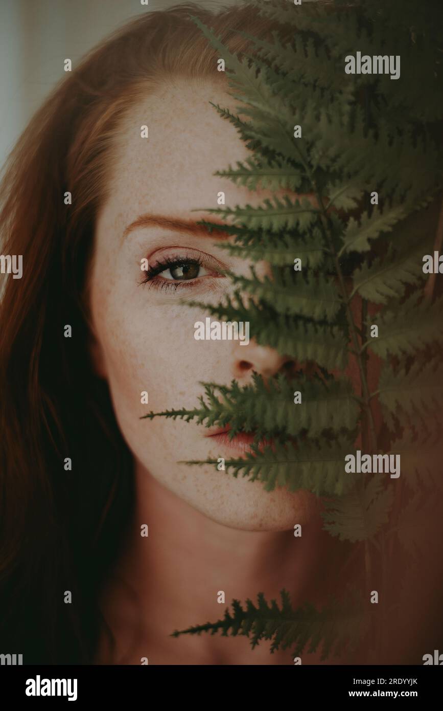 Primo piano di Redheaded Woman con Plant Foto Stock