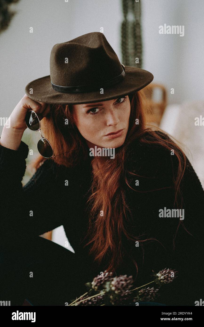Donna rossa con cappello e occhiali da sole Foto Stock