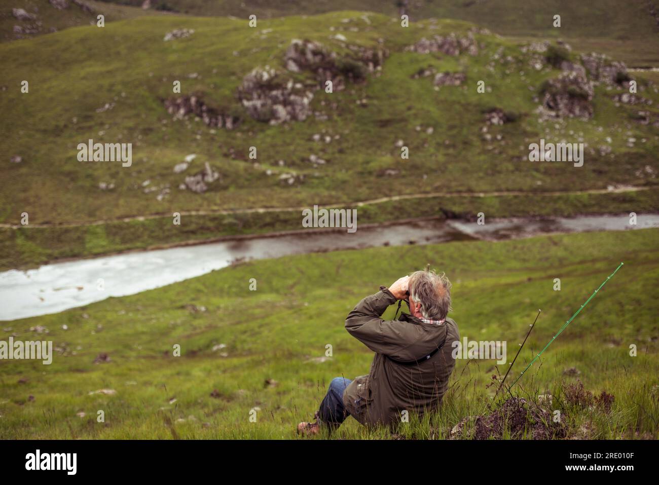 Un uomo in pensione maturo si affaccia sul fiume salmone in Scozia Foto Stock