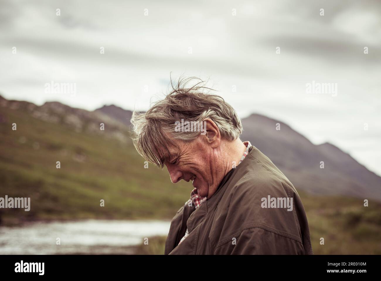 l'uomo in pensione ride e sorride pescando nella remota montagna fluviale Foto Stock