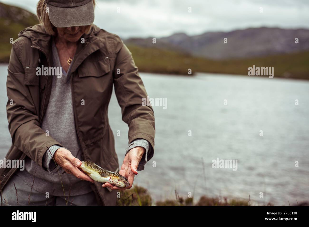 una donna in pensione tiene trote selvatiche catturate dal lago in scozia Foto Stock