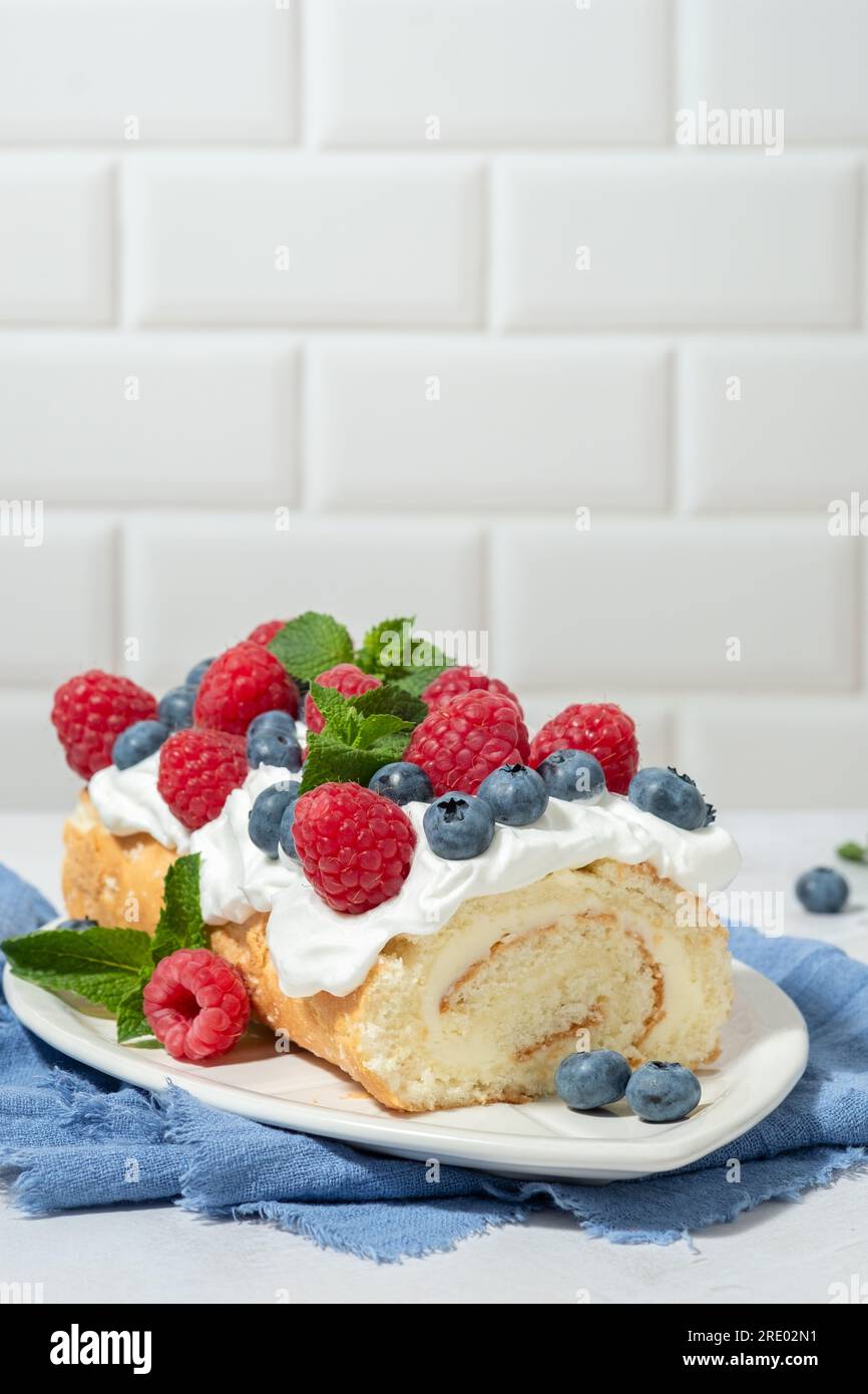 Panini con spugna, panna montata e frutti di bosco decorati con lamponi e mirtilli. Concetto di cibo estivo Foto Stock