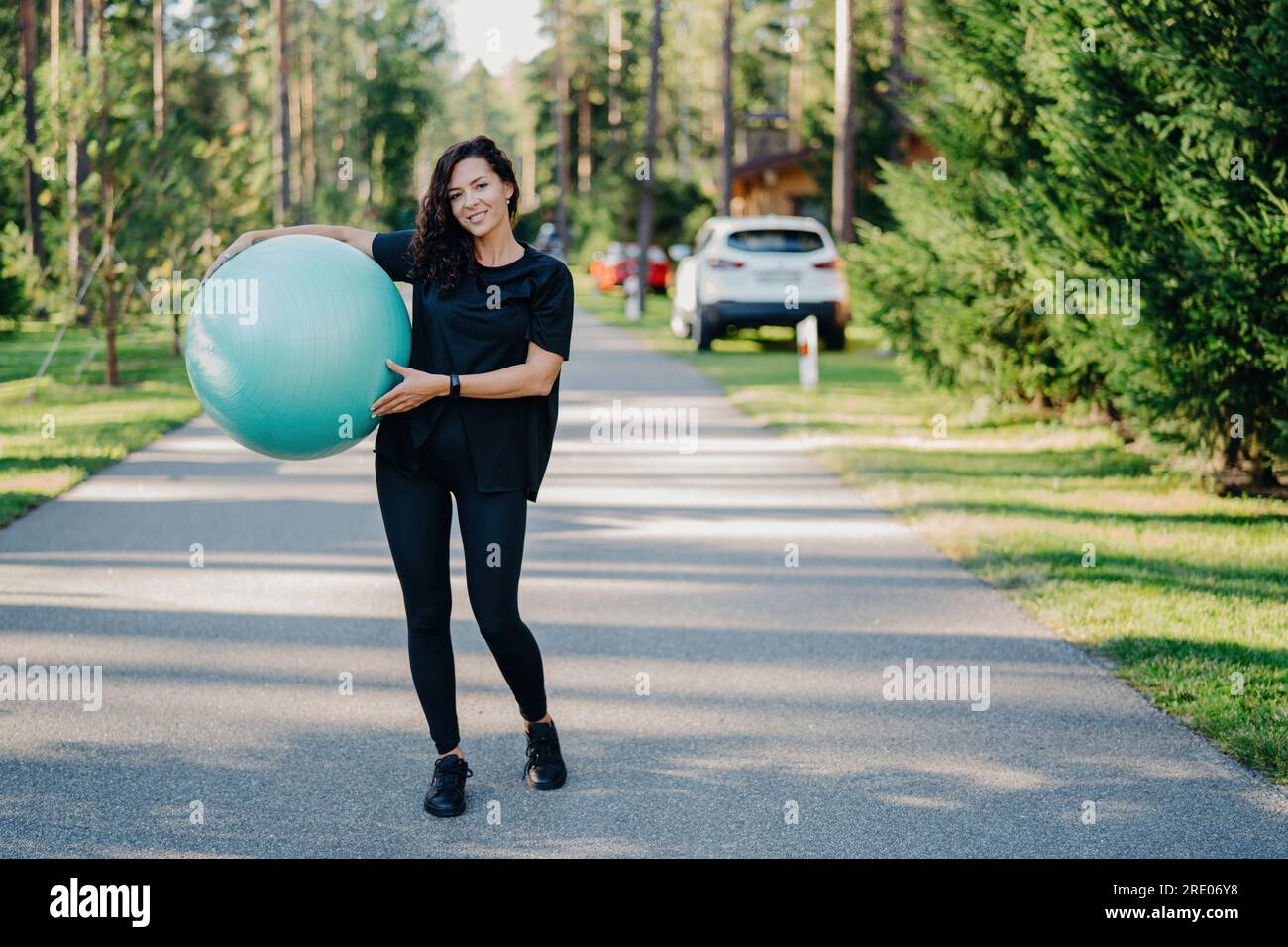 Donna attiva con esercizi di fitness all'aperto, per mantenersi in forma con abbigliamento sportivo. Abbracciare uno stile di vita sano vicino alla foresta. Ginnastica e aerobica. Foto Stock