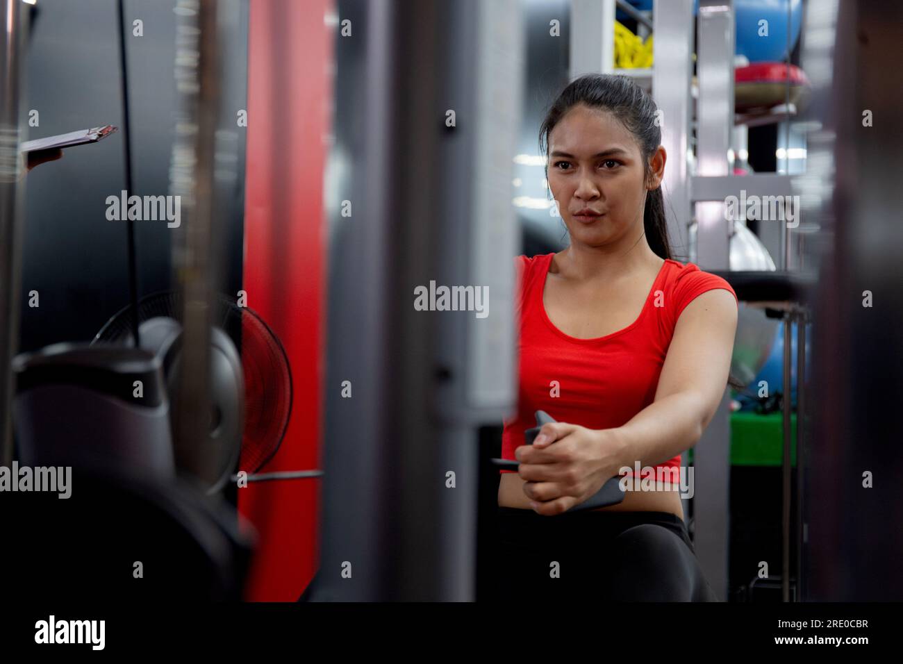 Allenamento per giovani donne asiatiche con allenamento di forza e determinazione con macchine fitness, energico esercizio asia Woman con motivazione in fitness Foto Stock
