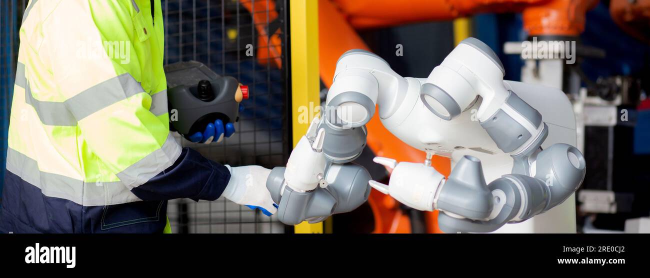 Giovane ingegnere uomo controllo e manutenzione macchina robot armi intelligenza e innovazione tecnologica in fabbrica industriale, tecnico esaminando robo Foto Stock