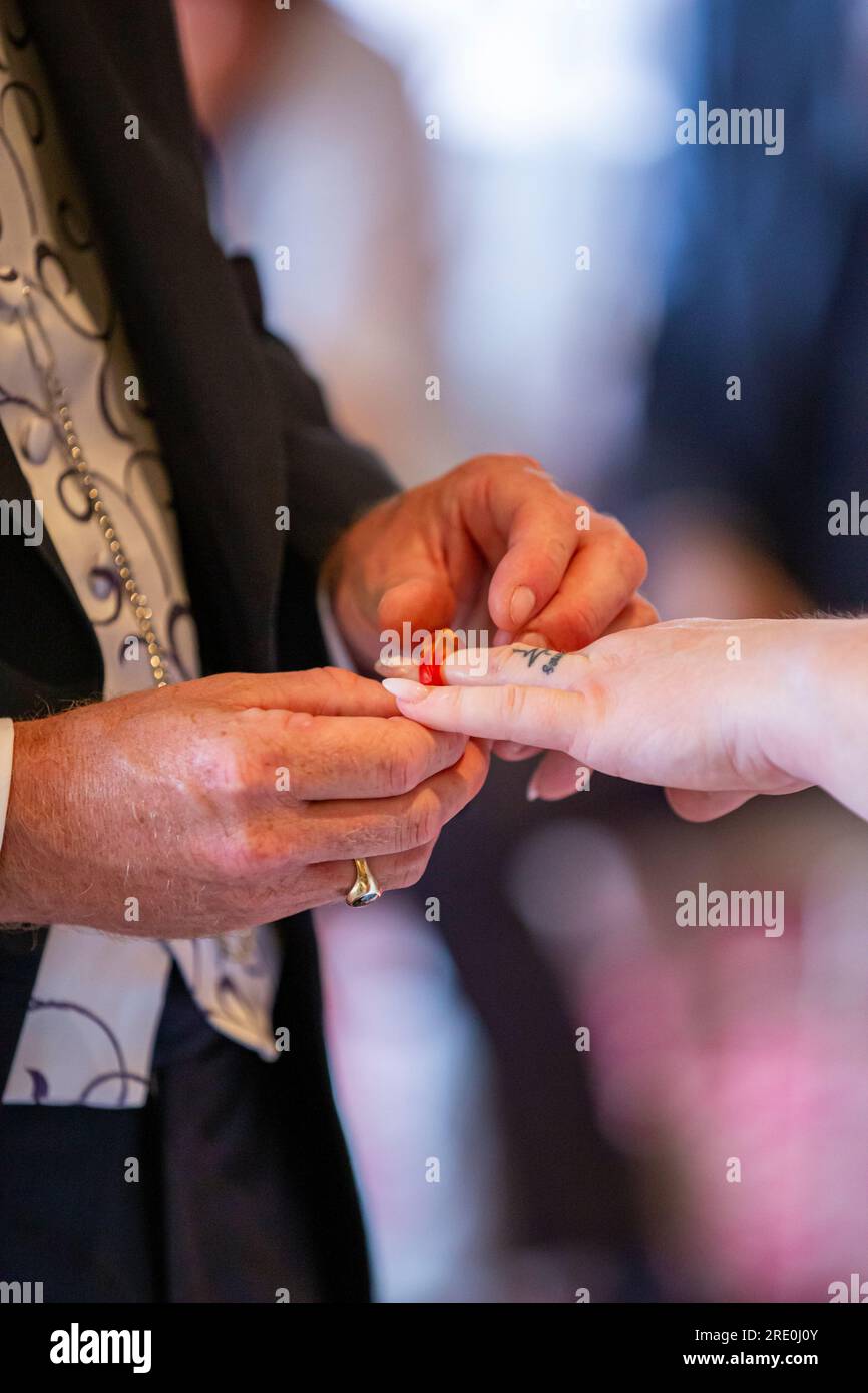 Un Groom che mette un anello di gelatina sul dito della sposa durante lo scambio di anelli durante una cerimonia Foto Stock