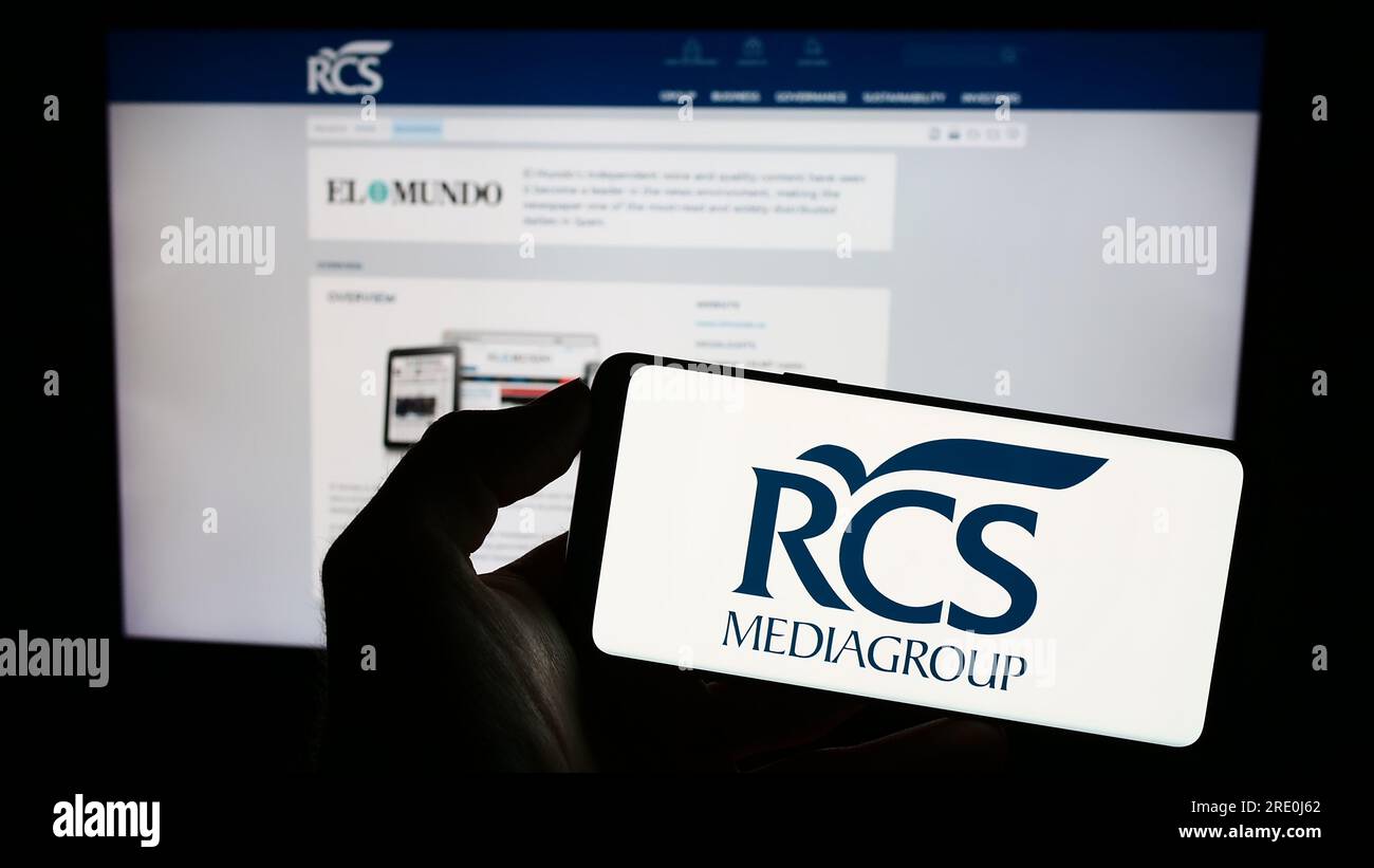 Persona in possesso di cellulare con logo della società italiana di media RCS MediaGroup Spa sullo schermo di fronte alla pagina web aziendale. Concentrarsi sul display del telefono. Foto Stock