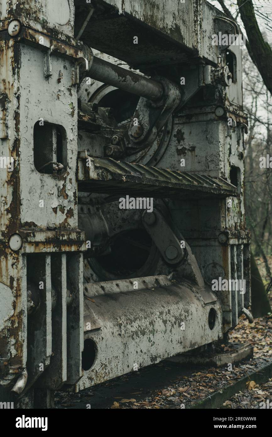 Una vecchia macchina defunta per la lavorazione delle lamiere nella foresta. Produzione di ferro e acciaio. Macchina per la storia industriale. Macchinari abbandonati e arrugginiti. Foto Stock