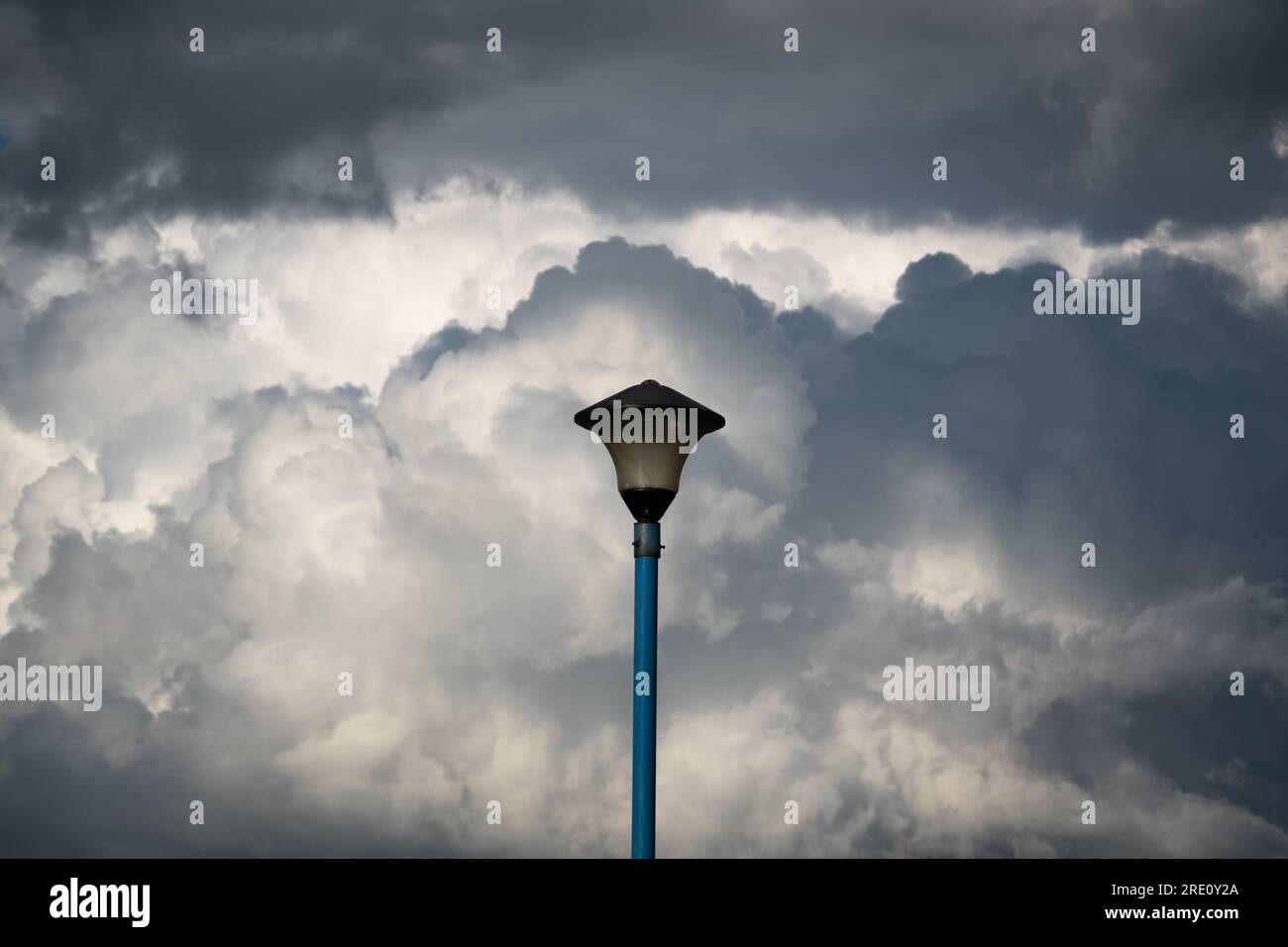 Lampione elettrico contro nuvole contrastanti, oggetto isolato Foto Stock