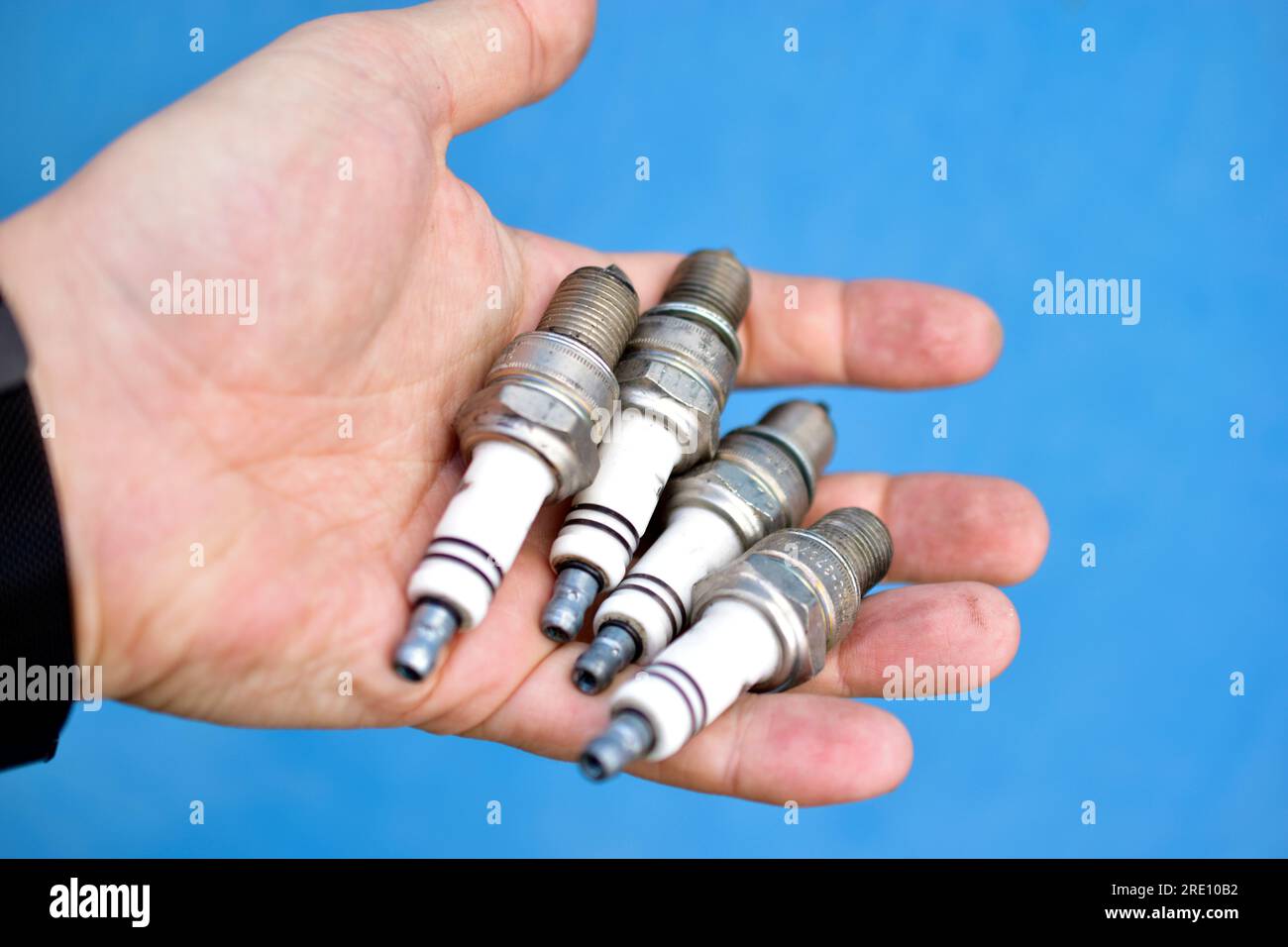 Quattro candele bianche per auto in mano su sfondo blu Foto Stock