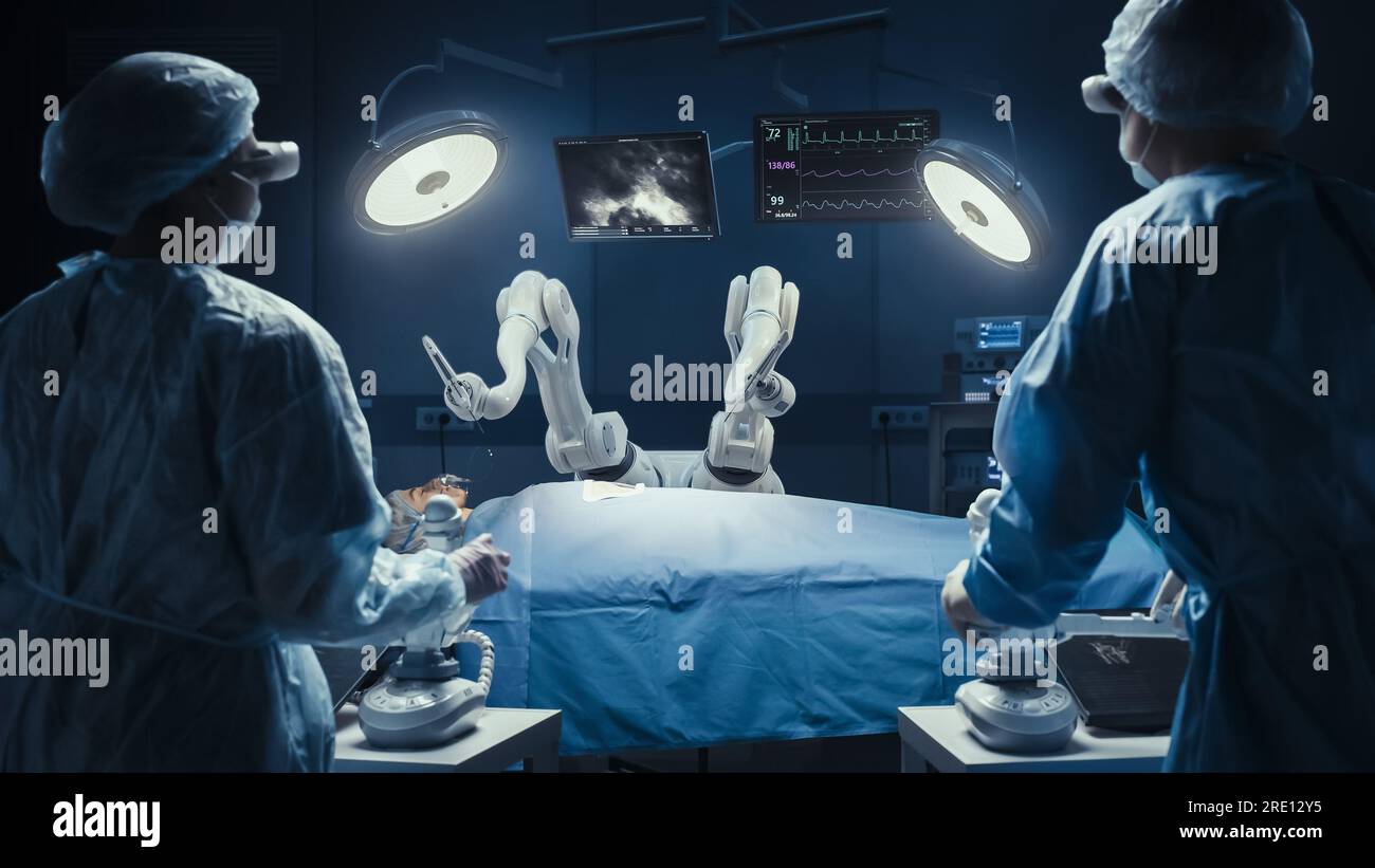 Due chirurghi che osservano i bracci robotici automatici programmabili ad alta precisione che utilizzano il paziente in ospedale ad alta tecnologia. Arti robotici che eseguono interventi chirurgici Foto Stock