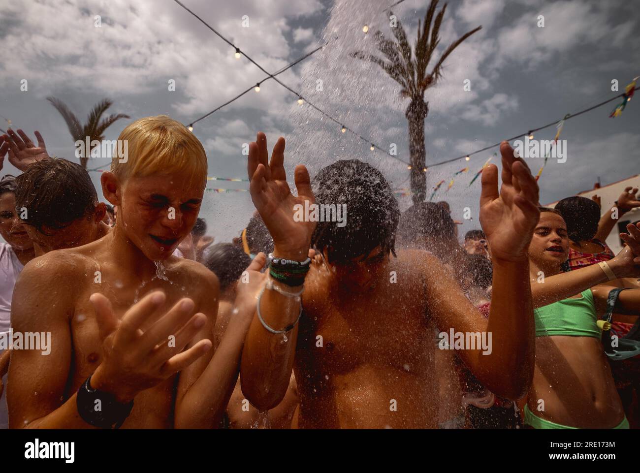 Fornells, Spagna. 24 luglio 2023. I partecipanti richiedono una doccia ad acqua durante una festa in schiuma alla ricerca di un po' di ristoro durante il tradizionale Festival di Sant Antoni, mentre l'isola soffre di alte temperature in un'altra ondata di calore. Crediti: Matthias Oesterle/Alamy Live News Foto Stock