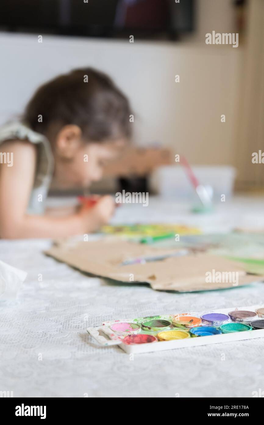 Dolce bambina che gioca con le pitture. Bambino che esplora la sua creatività dipingendo con gli acquerelli in un ambiente domestico. Foto Stock