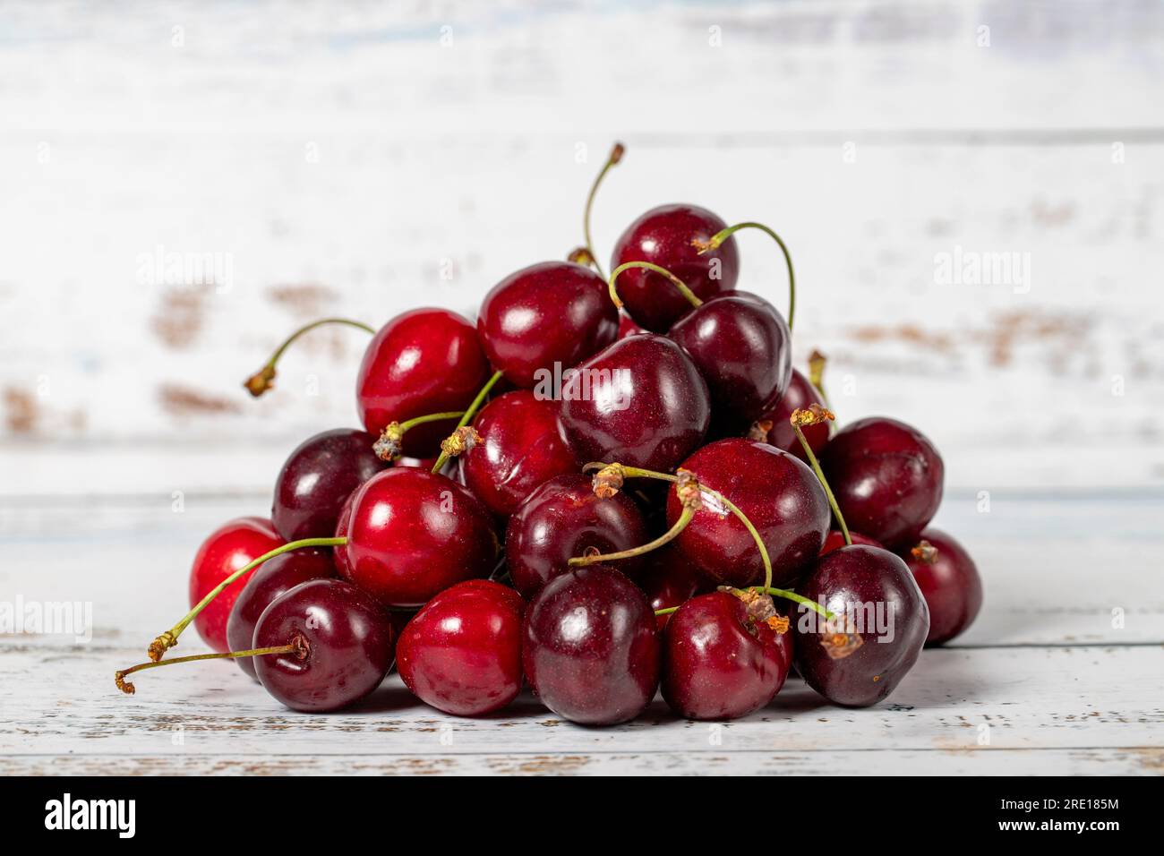 Ciliegia su sfondo di legno bianco. Concetto di stagione della vendemmia fresca ciliegia. Frutta sana e fresca Foto Stock