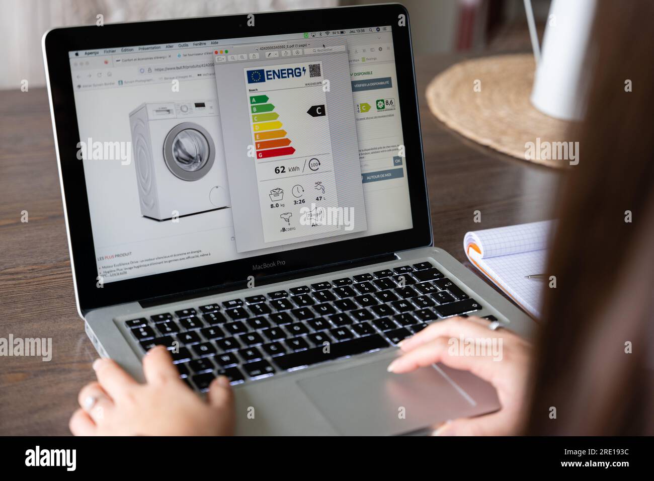 Una donna consulta l'etichetta energetica di una lavatrice presso un rivenditore di elettrodomestici online. Etichetta energetica che classifica gli apparecchi su una scala da A A G accordi Foto Stock Una donna consulta l'etichetta energetica di una lavatrice presso un rivenditore di elettrodomestici online. Etichetta energetica che classifica gli apparecchi su una scala da A A G accordi Foto Stock