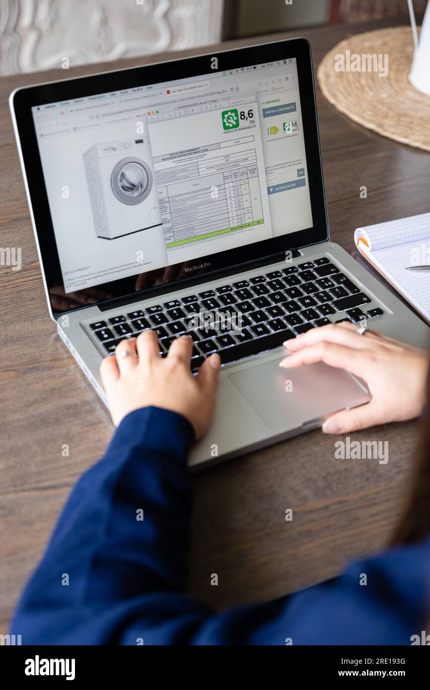 Una donna consulta l'etichetta riparabile di una lavatrice in un negozio web. I produttori devono indicare su una scala di A e quanto facilmente la loro devi Foto Stock Una donna consulta l'etichetta riparabile di una lavatrice in un negozio web. I produttori devono indicare su una scala di A e quanto facilmente la loro devi Foto Stock