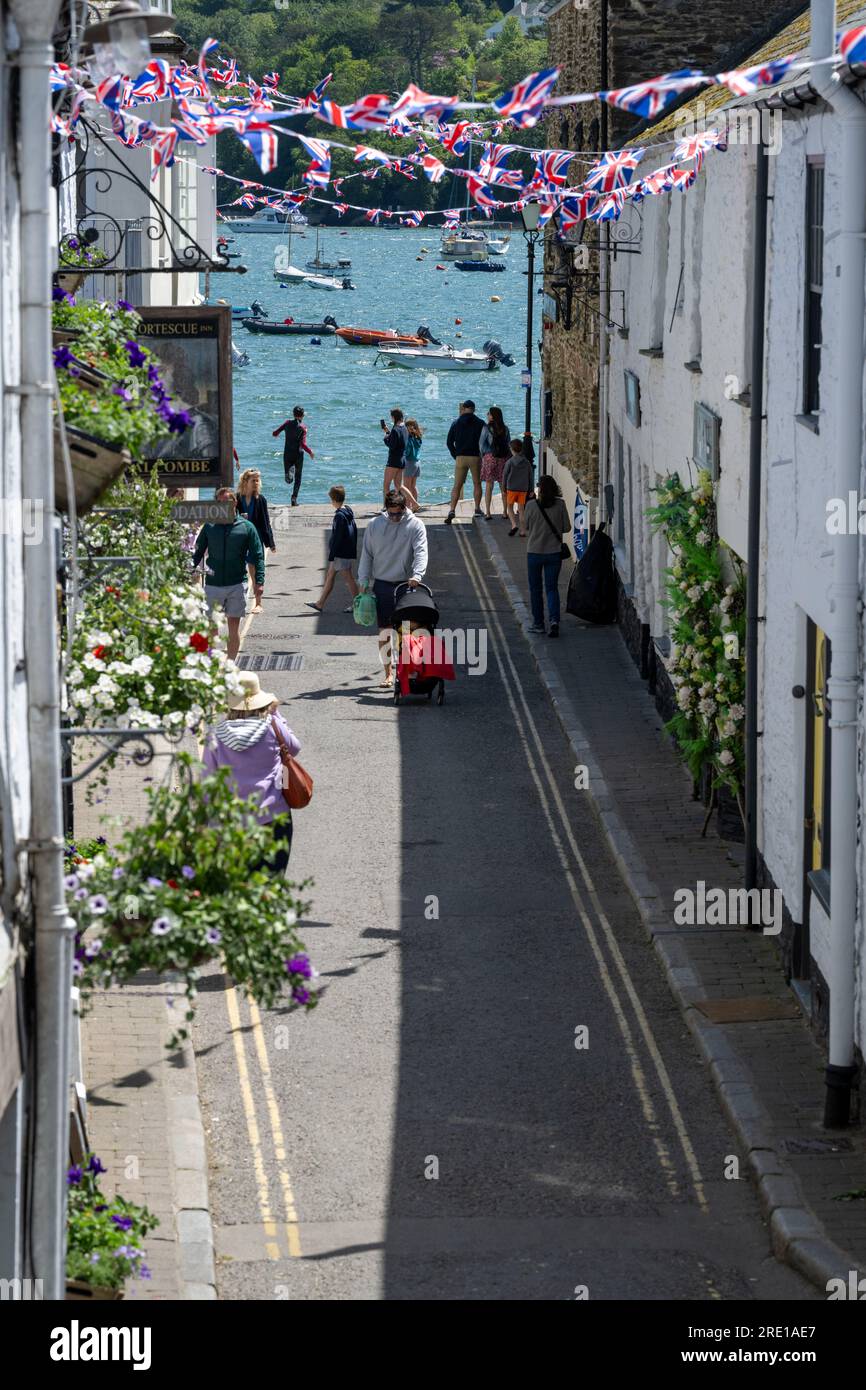 Ammira Fore Street, Salcombe, guardando verso le acque calme dell'estuario, Union Jack che vola con persone che vagano al sole. Foto Stock