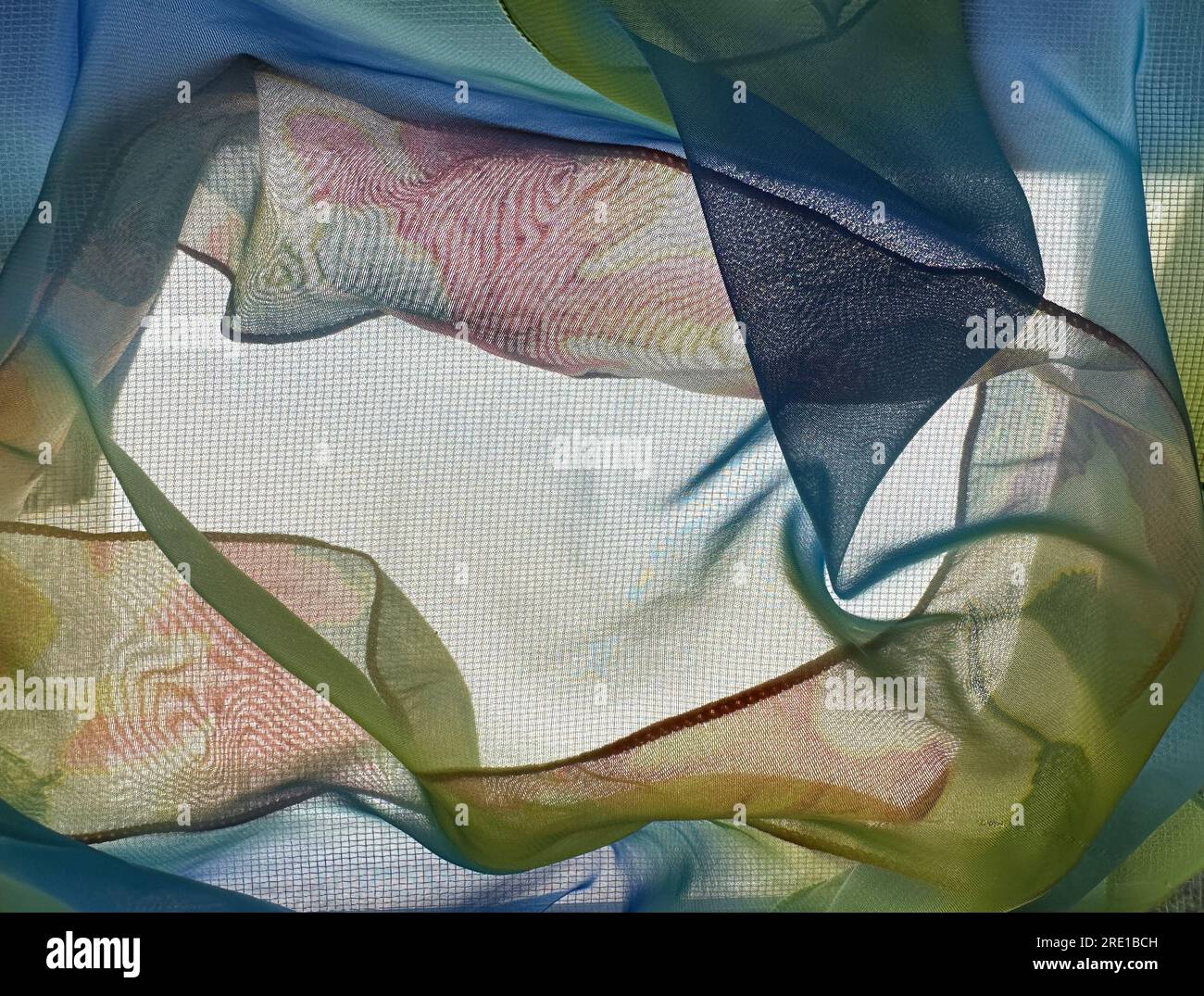 Lo spazio di testo è circondato da tessuti traslucidi retroilluminati con motivi a vortice e colori autunnali. Blu, giallo, verde e rosso sono i colori dei tessuti. Foto Stock