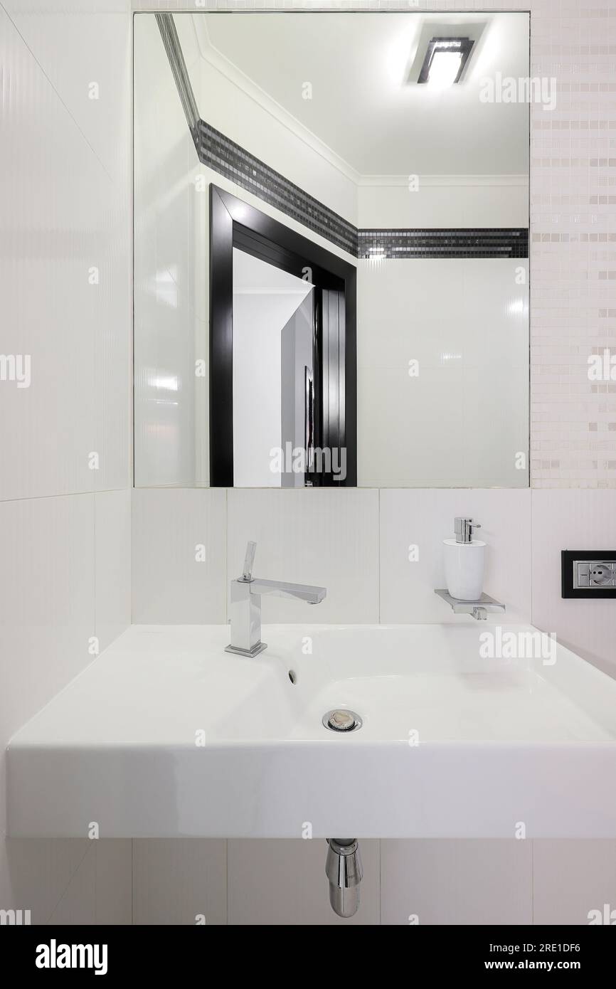 Rubinetto con lavabo in ceramica e specchio all'interno del bagno Foto Stock Rubinetto con lavabo in ceramica e specchio all'interno del bagno Foto Stock