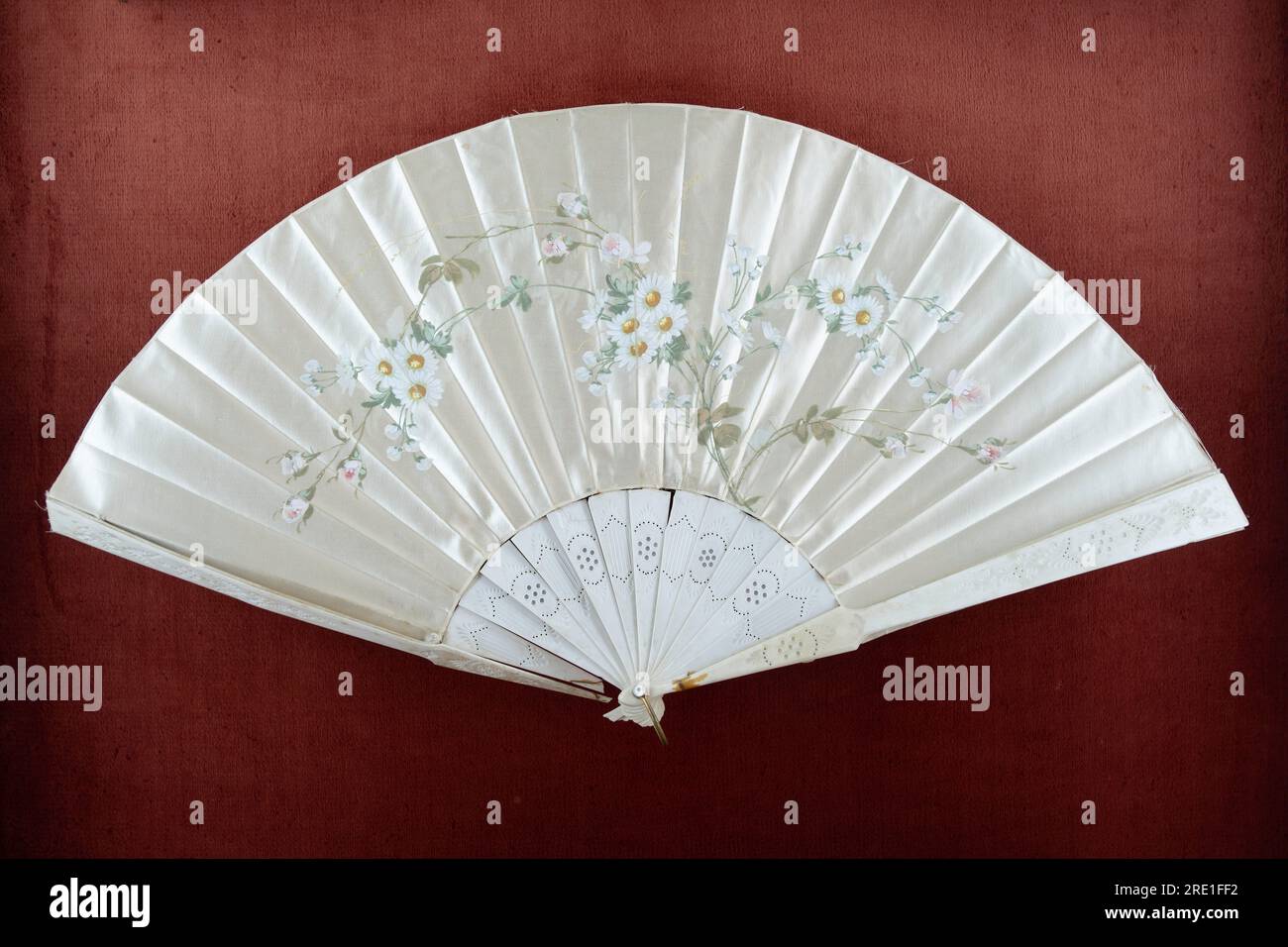 Splendido ventilatore a mano in seta antico con motivo floreale di fiori Fantasia, su sfondo in velluto rosso Foto Stock