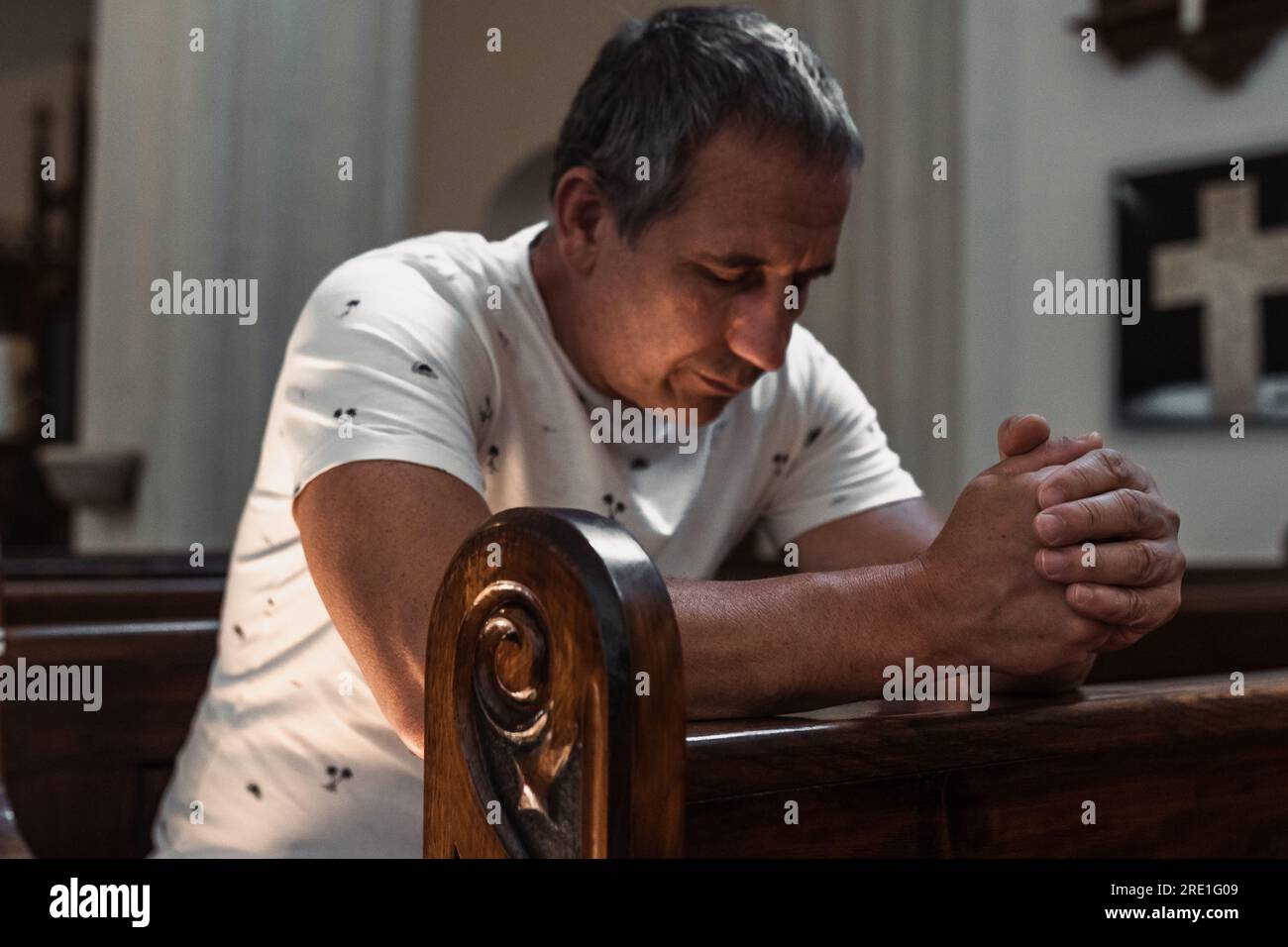 uomo che prega in chiesa Foto Stock