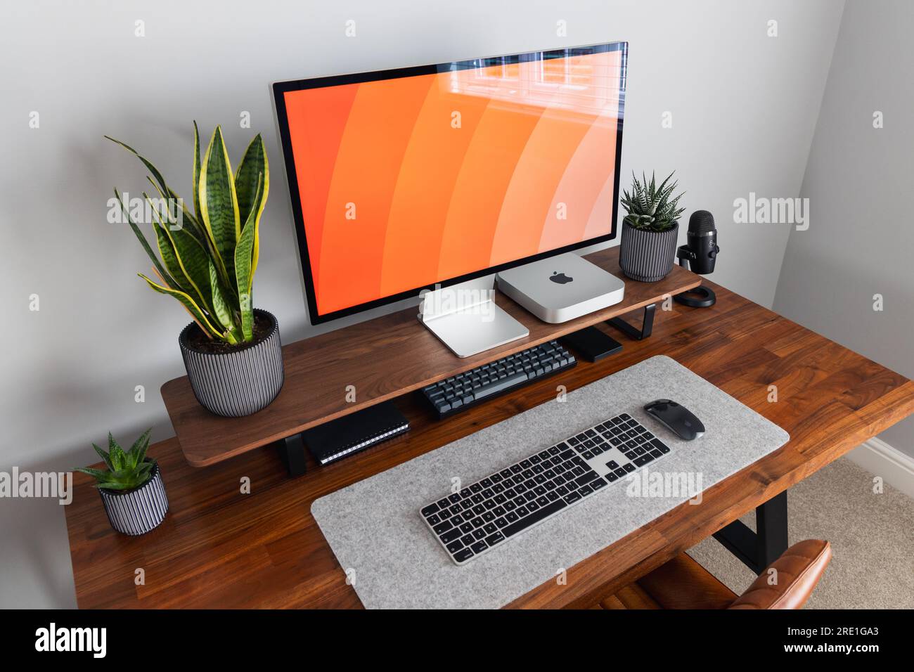 LONDRA - 12 LUGLIO 2023: Apple Studio display e Mac Mini computer in un moderno ufficio domestico, lavoro da casa configurazione minima della scrivania Foto Stock