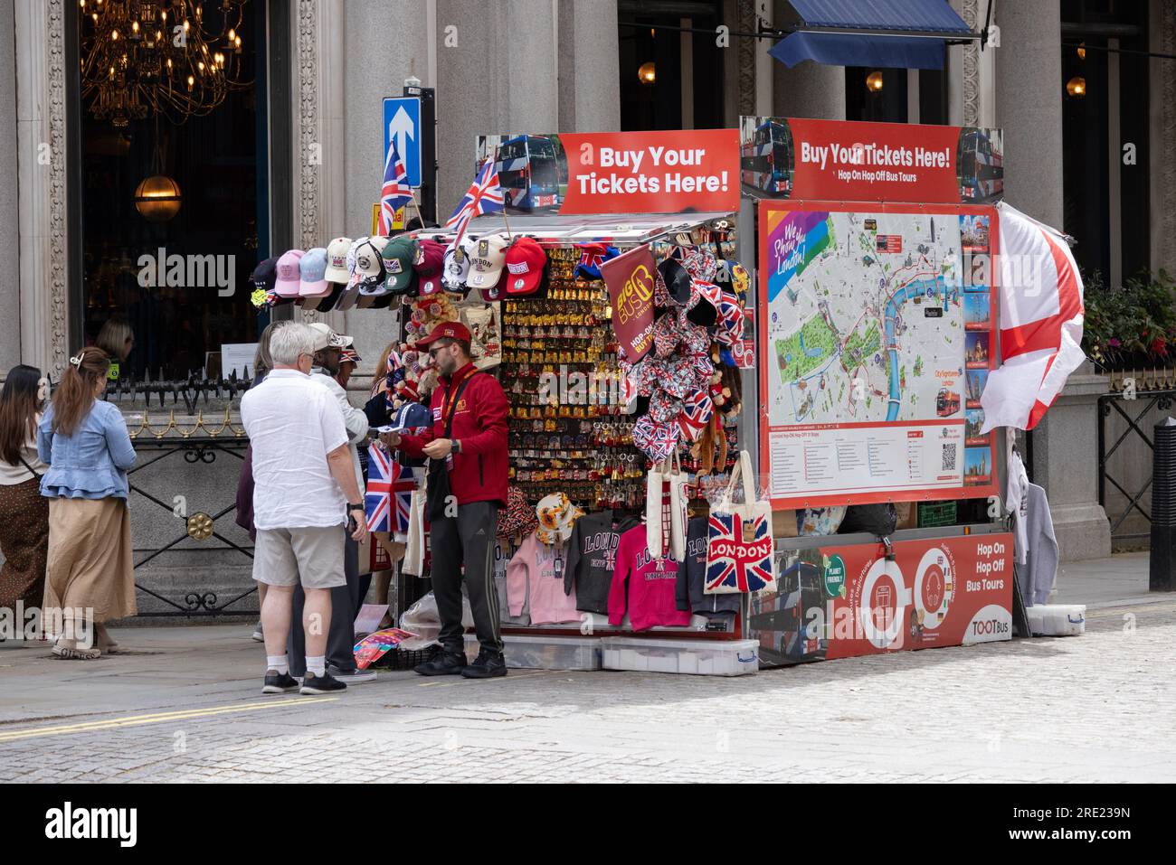 Turisti che acquistano souvenir da un chiosco che vende merce londinese su Oxford Street, Londra, Inghilterra, Regno Unito Foto Stock