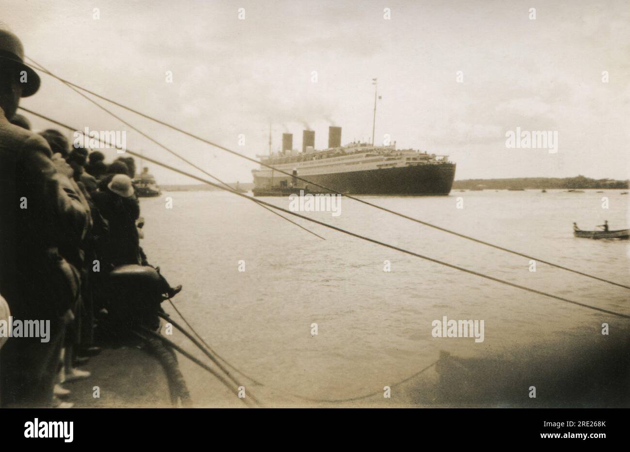 Southampton, Hampshire. c.1938 - la folla si radunò sulla banchina per osservare la nave passeggeri transatlantica Cunard-White Star Line, RMS Queen Mary, che salpava fuori dai porti di Southampton, aiutata da rimorchiatori. La nave fu costruita dalla John Brown & Company a Clydebank, in Scozia e salpò per il suo viaggio inaugurale il 27 maggio 1936. A parte un periodo durante la seconda guerra mondiale, quando fu convertita e impiegata come nave da guerra, rimase in servizio fino al 1967. Ha vinto il premio Blue Riband per la traversata transatlantica più veloce nell'agosto 1936 e poi di nuovo nel 1938, mantenendolo fino al 1952. Foto Stock