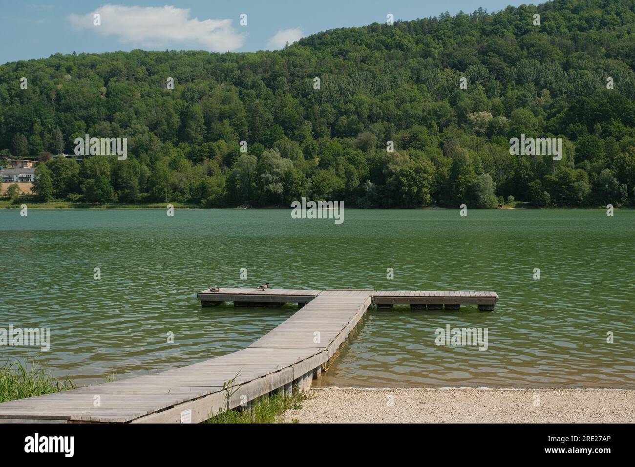 Una scena tranquilla ai piedi del lago Happurg, Germania, caratterizzata da un pittoresco molo di legno che si estende nelle acque tranquille. Foto Stock