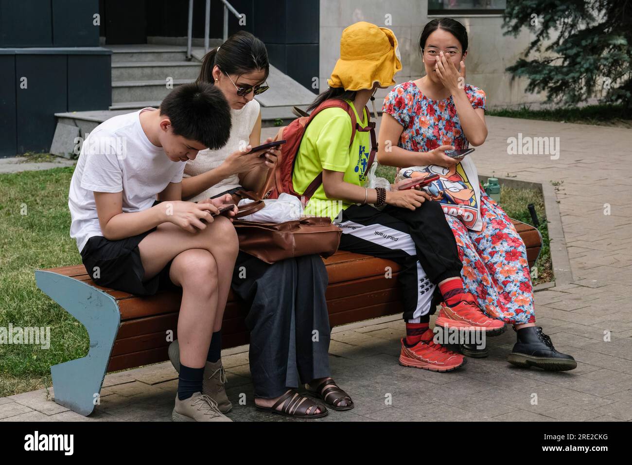 Kazakistan, Almaty. Scena stradale: Controllo dei telefoni cellulari in attesa di un autobus. Foto Stock