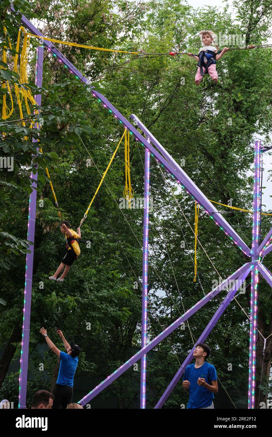 Kazakistan, Almaty. Kok-Tobe Park. Young Boys and Girls Swinging in the Air su corde elastiche. Foto Stock