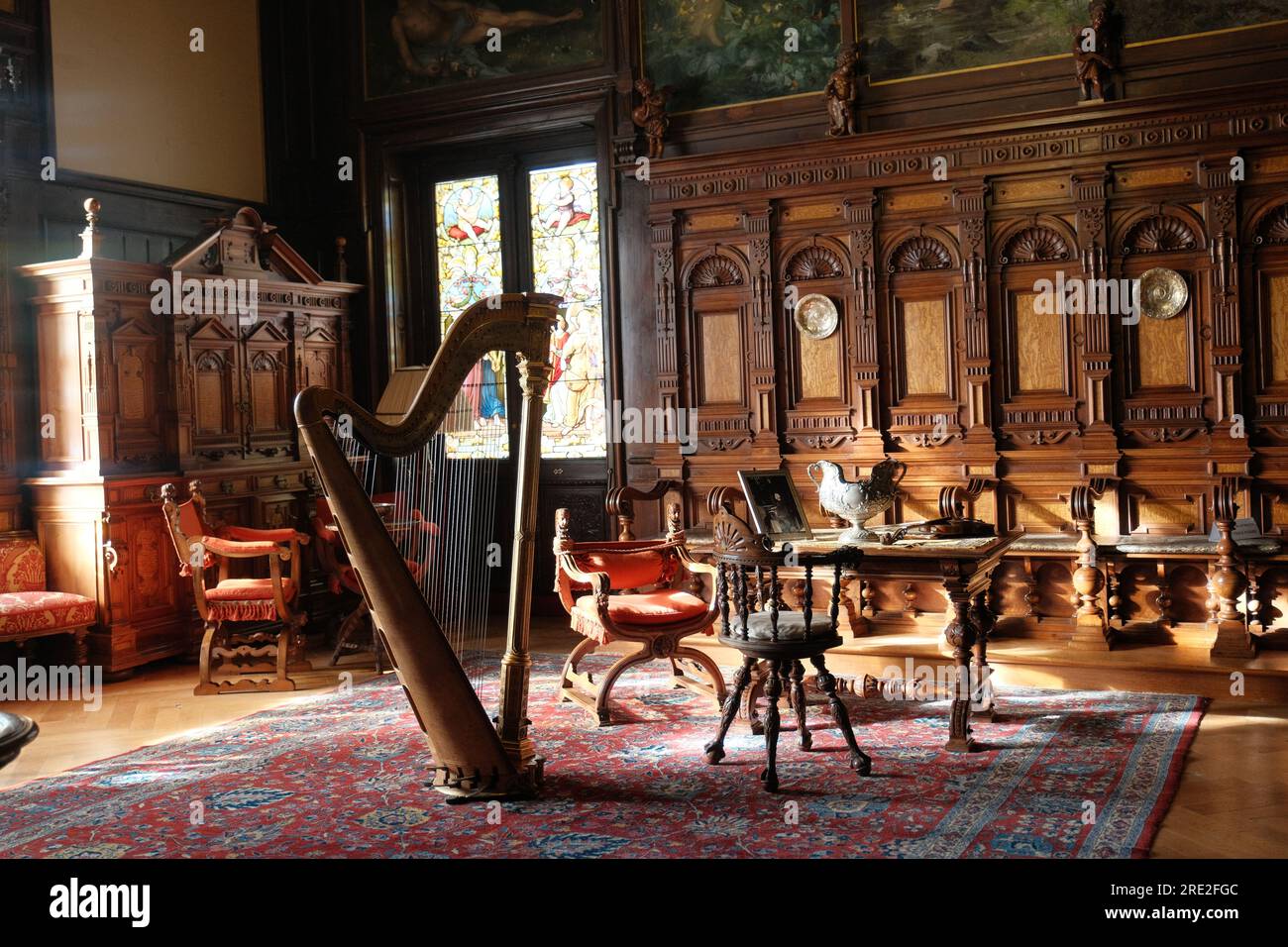 La camera di musica di un castello rumeno, inondata dalla luce soffusa che filtra attraverso le finestre, ospita una maestosa arpa, che emana un'aura di eleganza Foto Stock