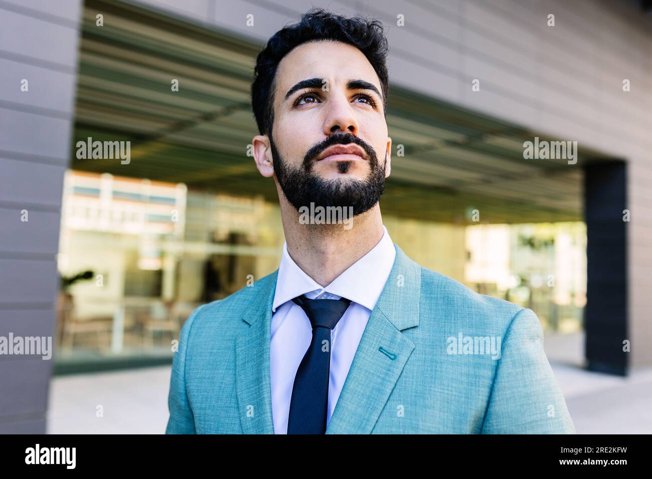 Un giovane uomo d'affari di successo e premuroso in abito all'esterno di un ufficio di edifici urbani Foto Stock