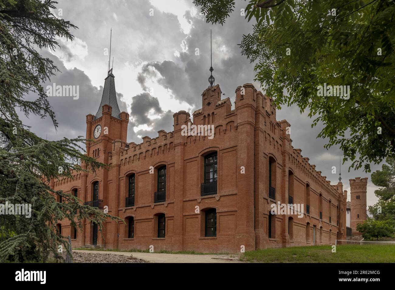 Edificio in mattoni d'epoca con una torre quadrata nel mezzo di un parco urbano Foto Stock