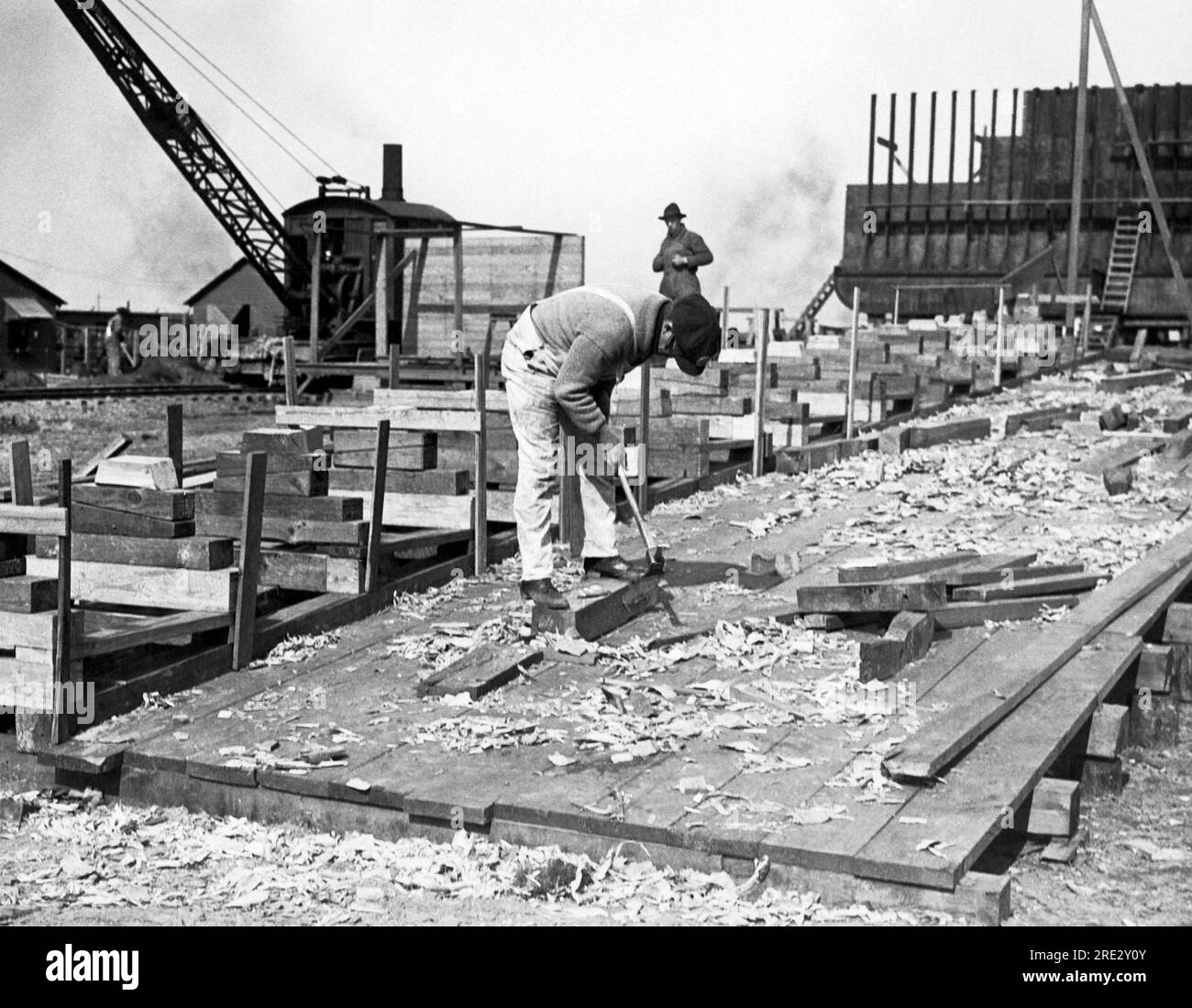 Philadelphia, Pennsylvania: 16 aprile 1918 Un lavoratore usa un adze mentre costruisce una chiglia modello presso la scuola per i costruttori navali del cantiere di Hog Island. Foto Stock