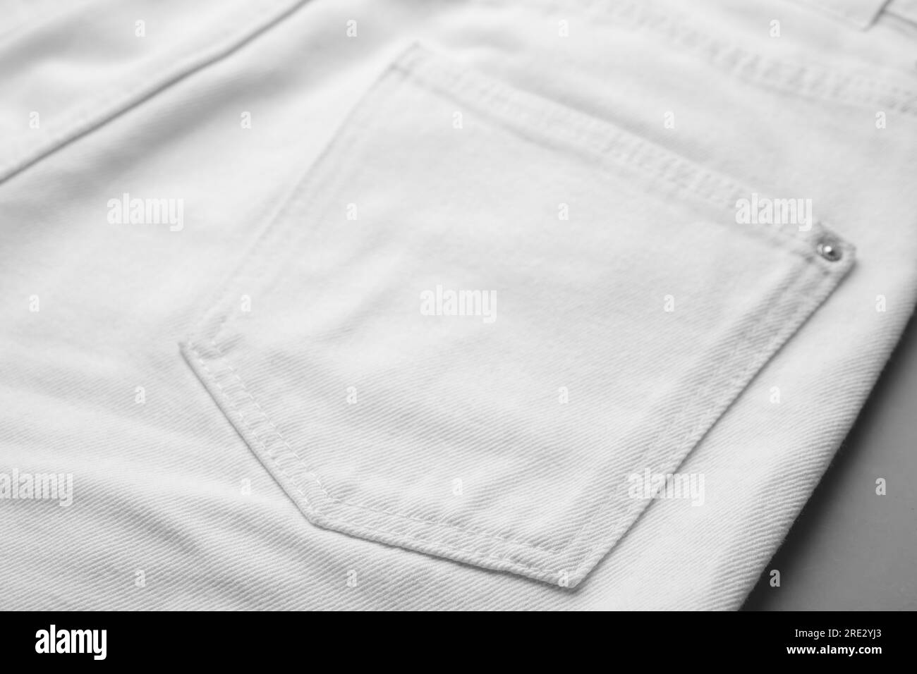 Jeans bianchi con tasca su sfondo grigio, primo piano Foto Stock