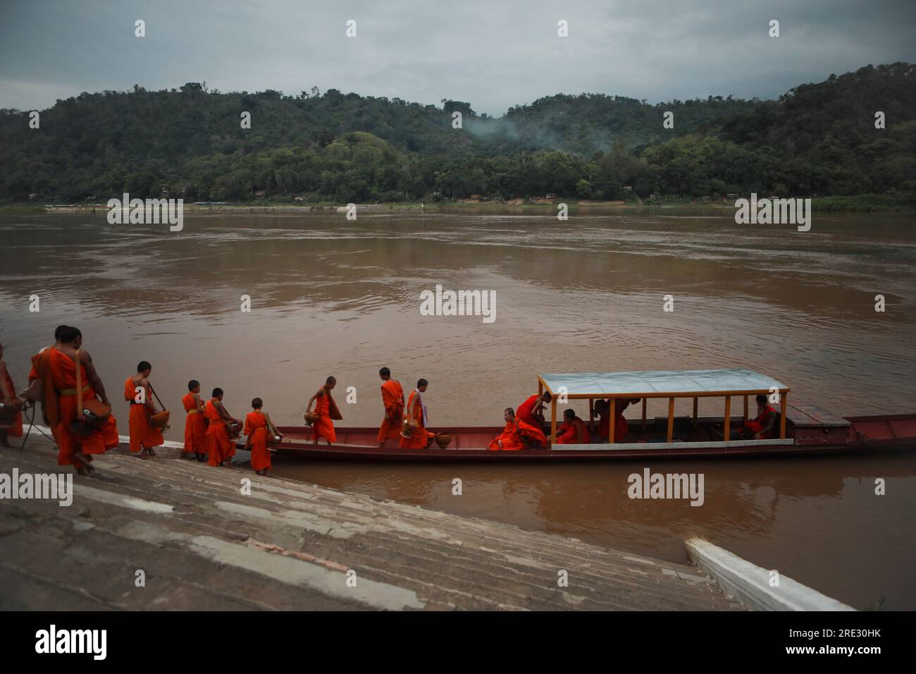 luang prabang-july19.2023 : monaco buddista si avvicina alla barca interna al tempio di wat xiang thong accanto al fiume maekong a luang prabang a nord di Foto Stock