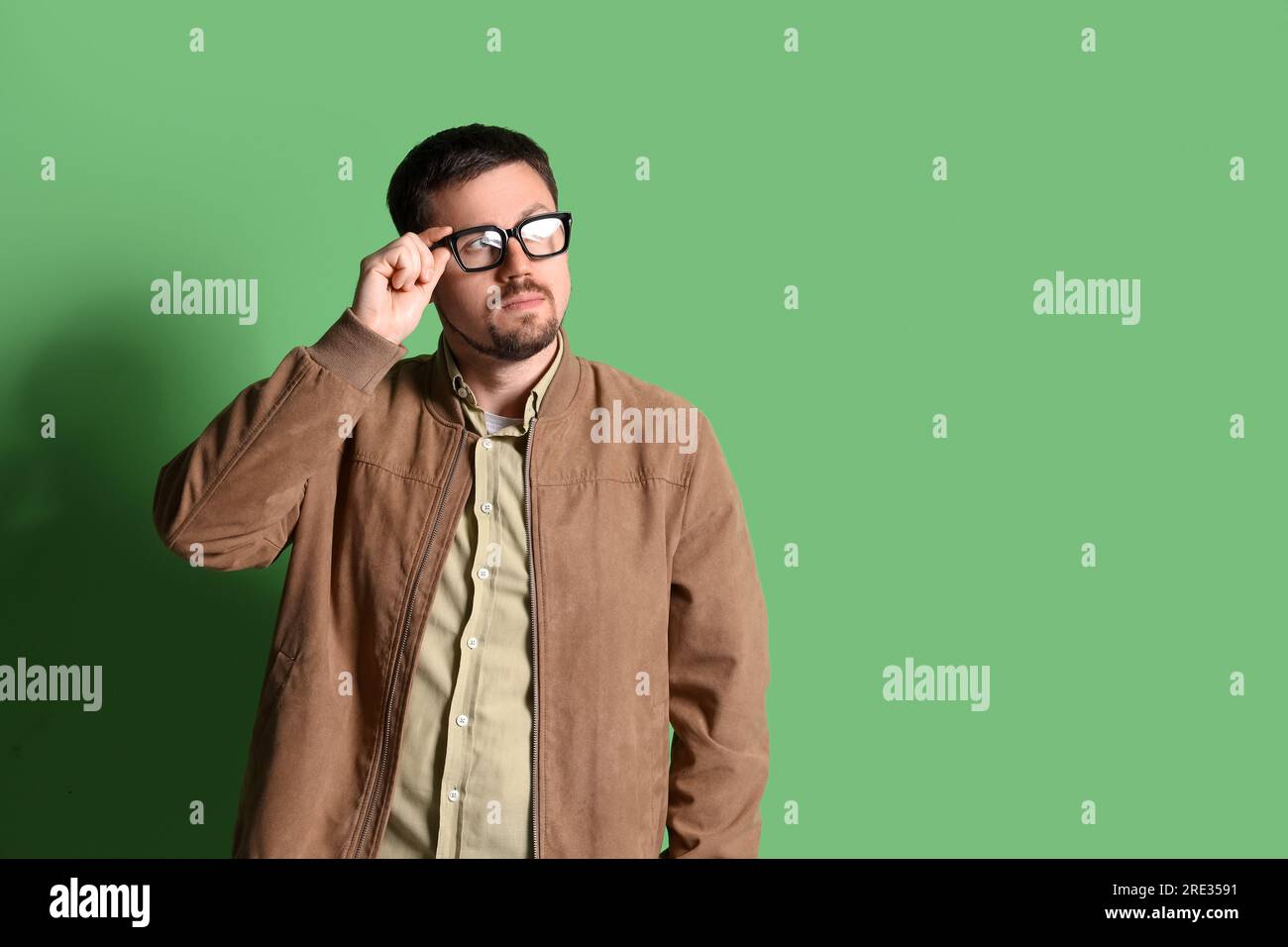 Bell'uomo in occhiali eleganti su sfondo verde Foto Stock