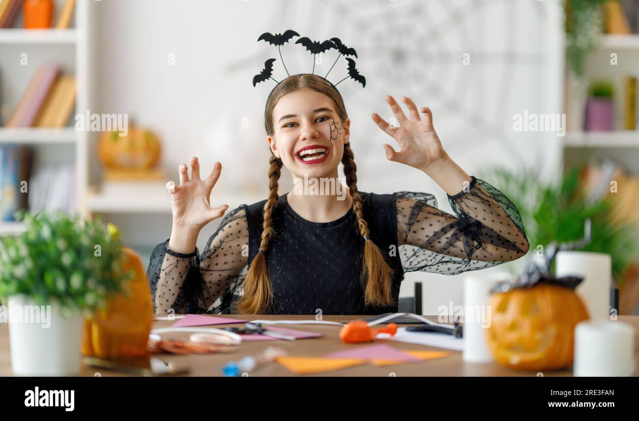 Adorabile adolescente con zucca intagliata. Ragazza felice che si prepara per Halloween. Divertente ragazzo a casa. Foto Stock