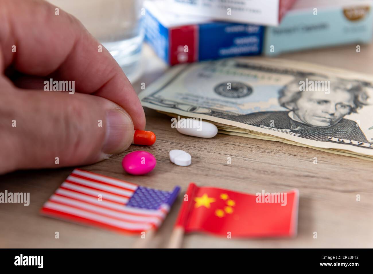 Un concetto di conflitto farmaceutico, medico e farmaceutico con le bandiere americane e cinesi, le banconote in dollari americani e varie medicine su una scrivania. Foto Stock
