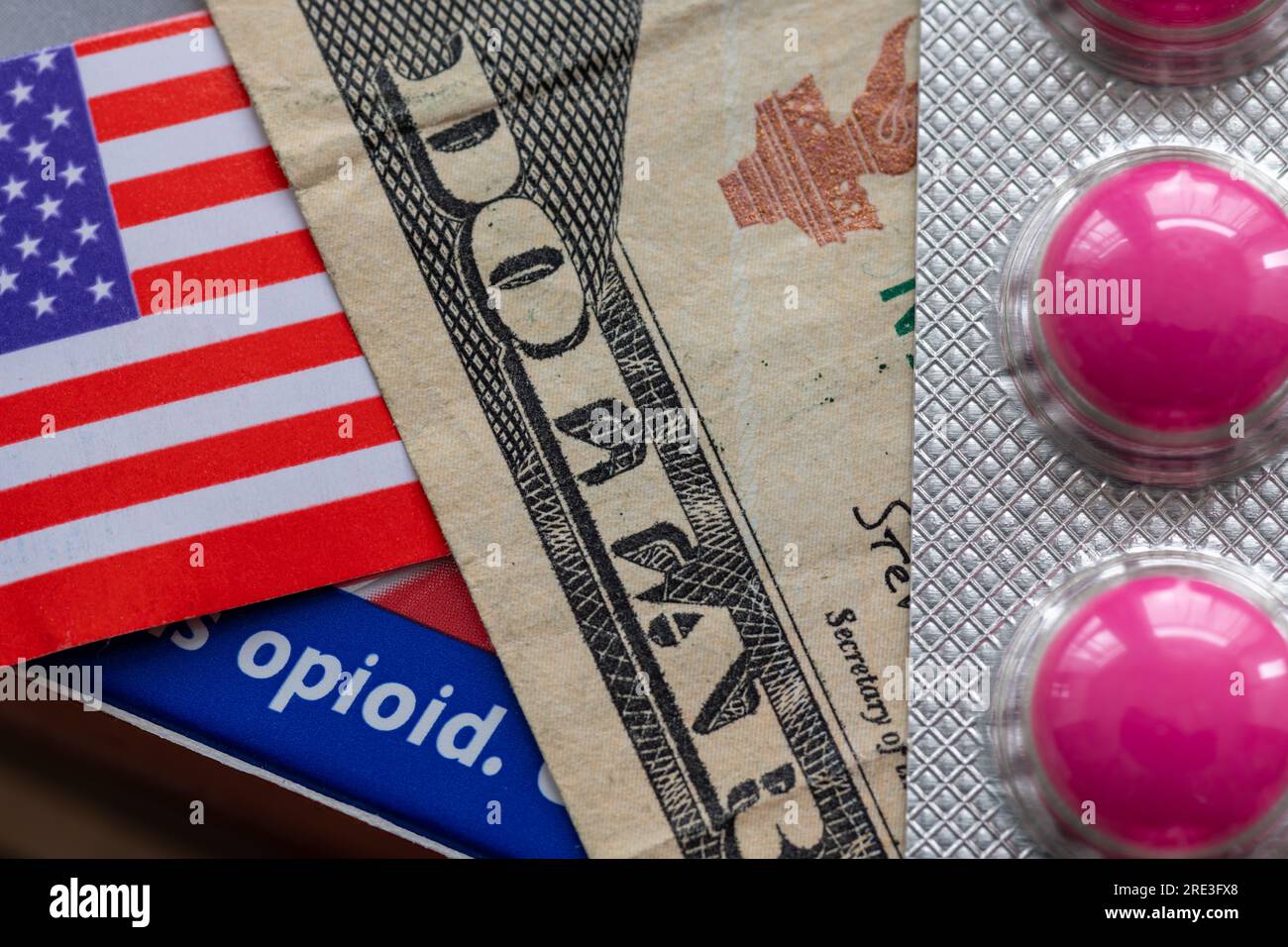 Un concetto di dipendenza da oppioidi con una banconota da dollaro, una bandiera americana e la parola oppioide su una scatola di medicine. Foto Stock