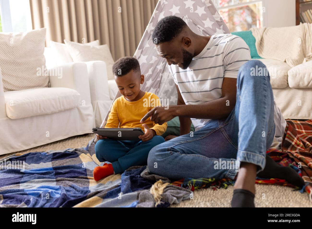 Padre e figlio afroamericani felici che usano il tablet a casa Foto Stock