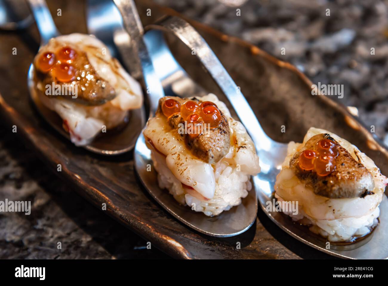 Piatti giapponesi, sushi di fusione con Fole Gras, uova di salmone e gamberi serviti in un cucchiaio Foto Stock