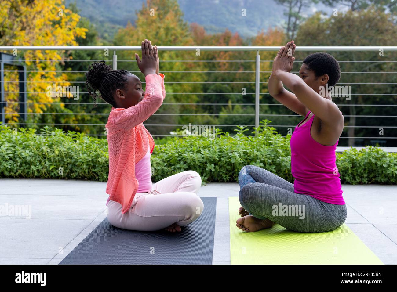 Madre e figlia afroamericane che praticano yoga sulla terrazza soleggiata a casa Foto Stock