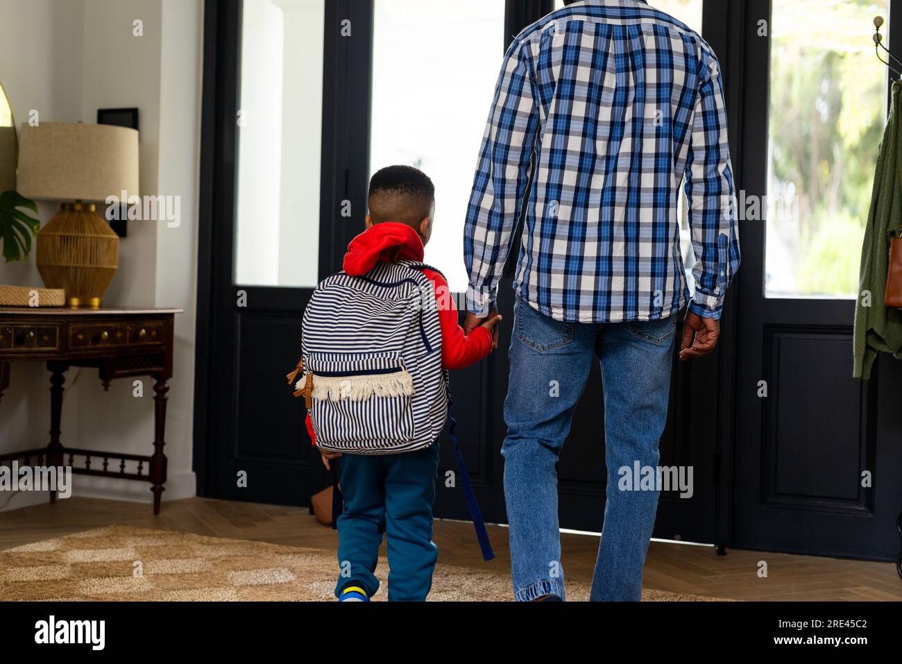 Sul retro di un padre afroamericano che tiene un figlio davanti alla porta a casa Foto Stock